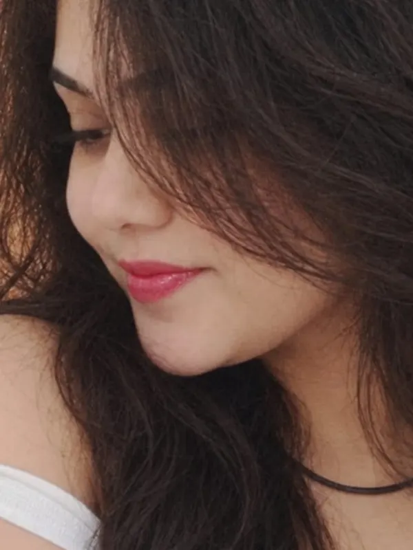 Close portrait of Manu glancing down, hair across her cheek.