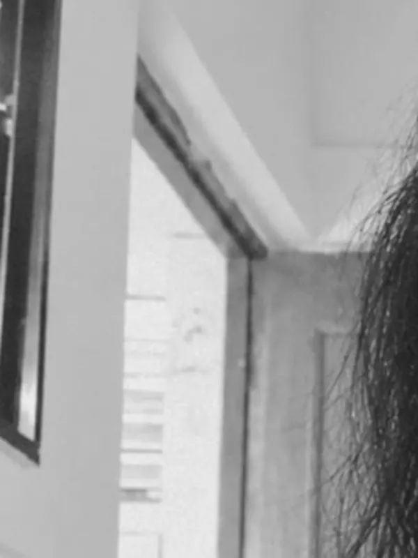 Black and white study of the doorway and window light beside her.