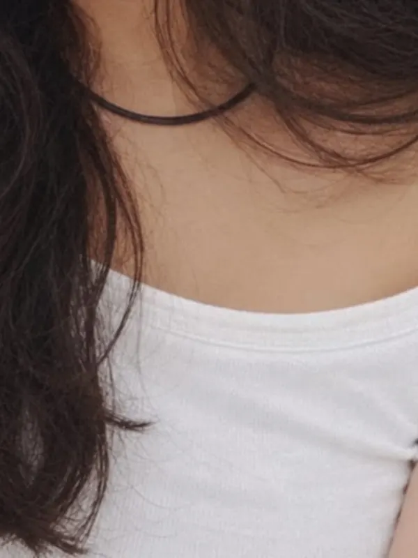 A black cord necklace against a white neckline.