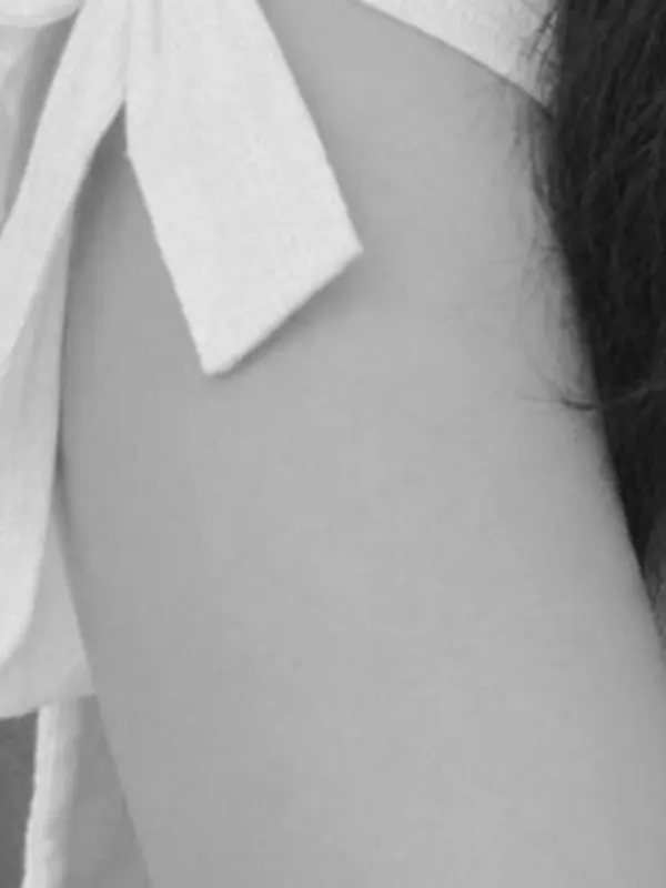 Black and white detail of a ribbon tie and shoulder.