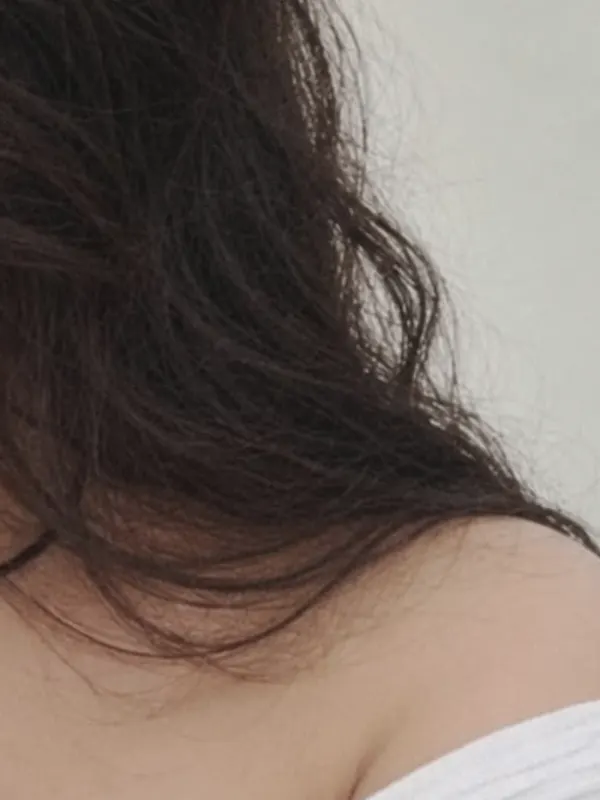 Long dark hair falling over a white shoulder.